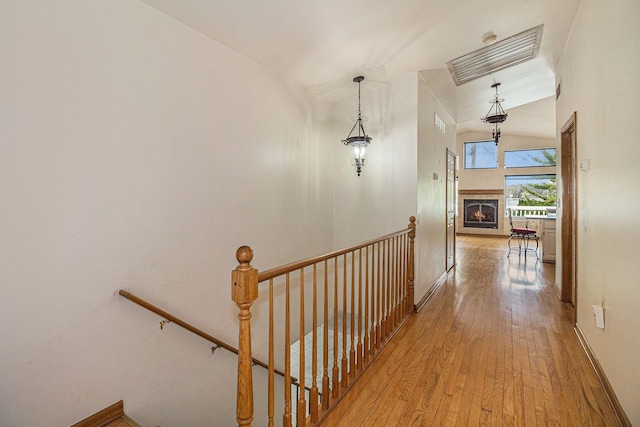hall with baseboards, an upstairs landing, and hardwood / wood-style flooring