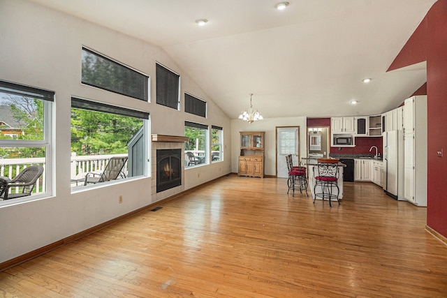 living room with an inviting chandelier, light wood finished floors, baseboards, and a fireplace