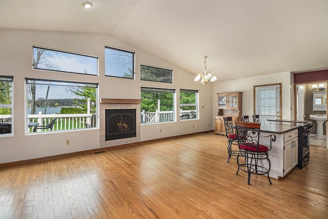 interior space featuring visible vents, lofted ceiling, a fireplace, light wood-style floors, and a notable chandelier