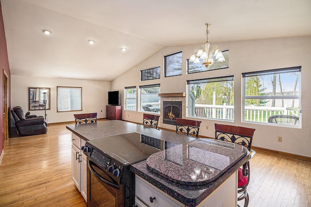 kitchen with black / electric stove, a notable chandelier, light wood finished floors, and open floor plan
