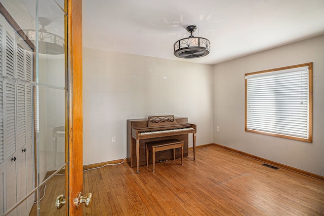 sitting room featuring visible vents, light wood-style floors, and baseboards