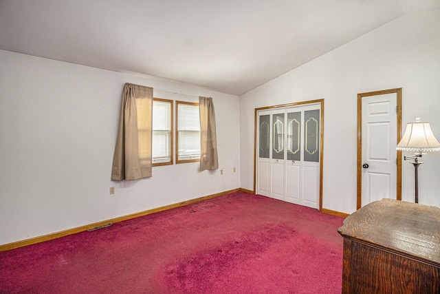 interior space with baseboards, vaulted ceiling, dark carpet, and visible vents