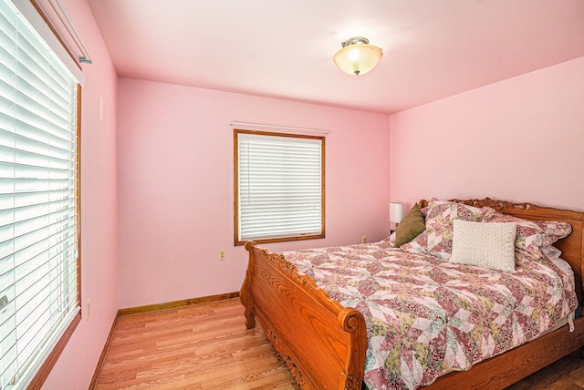 bedroom featuring baseboards, multiple windows, and light wood-style flooring