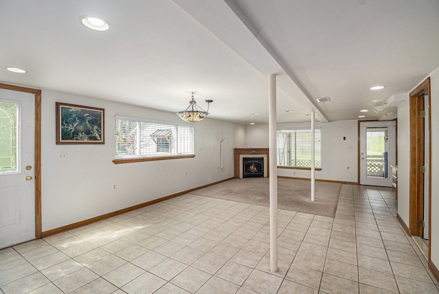 unfurnished living room featuring baseboards, light tile patterned flooring, and a healthy amount of sunlight