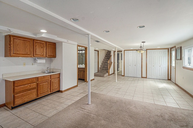 kitchen with brown cabinets, light tile patterned floors, baseboards, a sink, and light countertops