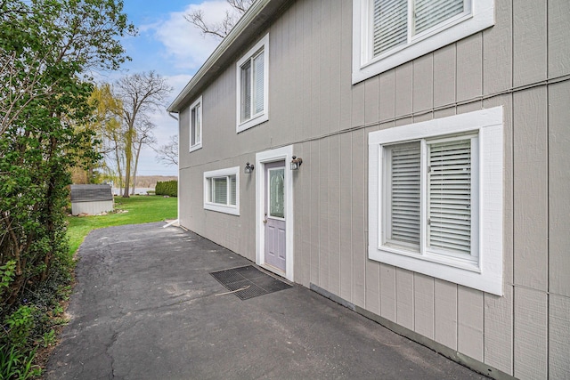view of home's exterior with an outdoor structure, a patio area, and a storage shed