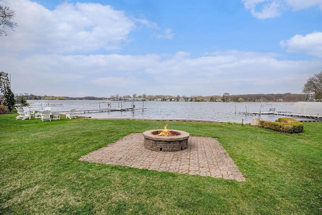 view of yard with a patio, a water view, an outdoor fire pit, and a boat dock