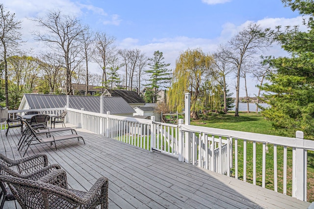 wooden terrace featuring a lawn, a water view, and outdoor dining area