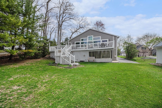 rear view of property featuring stairs, a lawn, and a deck