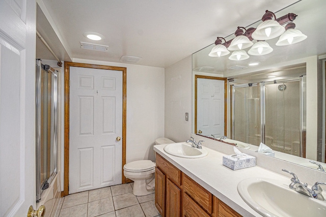bathroom featuring tile patterned flooring, a sink, a shower with shower door, and toilet