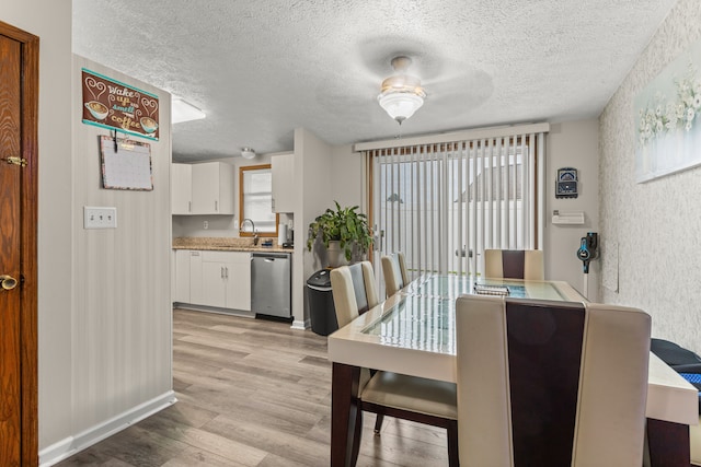 dining area featuring light wood-style flooring, baseboards, and a textured ceiling
