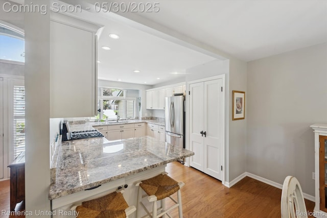 1317 Peppergrove Dr, Brighton, MI 48116 - kitchen with freestanding refrigerator, a sink, light wood finished floors, light stone counters, and a kitchen breakfast bar