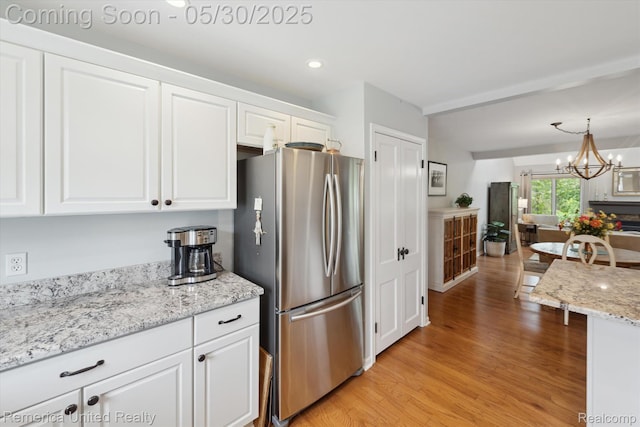 1317 Peppergrove Dr, Brighton, MI 48116 - kitchen featuring freestanding refrigerator, white cabinetry, light wood finished floors, a chandelier, and recessed lighting
