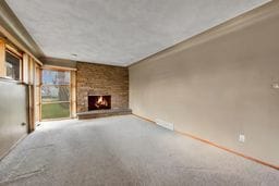 unfurnished living room with carpet flooring and a brick fireplace