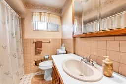 full bathroom with vanity, wainscoting, curtained shower, toilet, and tile walls