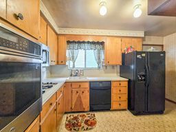 kitchen with brown cabinetry, light countertops, a sink, and black appliances