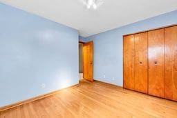 unfurnished bedroom featuring baseboards, a closet, and light wood-type flooring