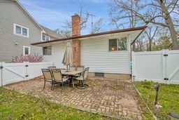 back of house featuring a fenced backyard, a gate, a chimney, and a patio area