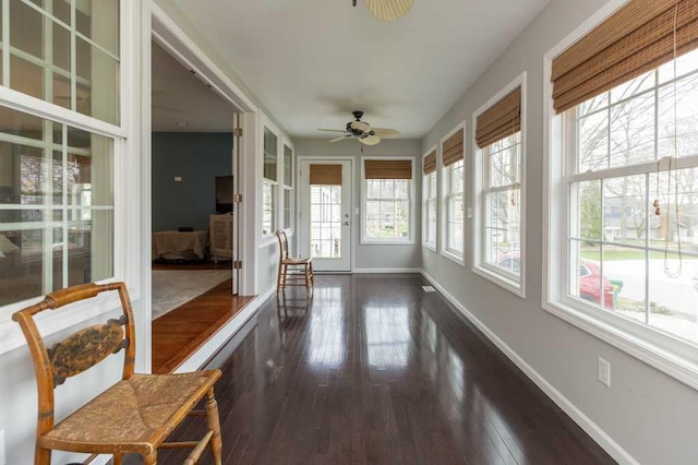 sunroom featuring baseboards and wood finished floors