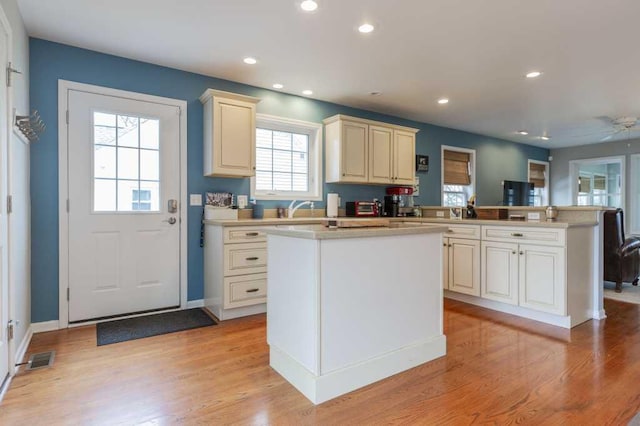kitchen with a peninsula, visible vents, light wood-type flooring, and light countertops