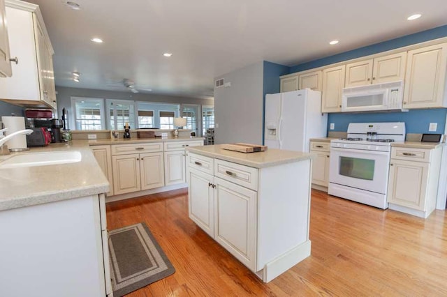 kitchen featuring a ceiling fan, a sink, white appliances, light wood finished floors, and recessed lighting