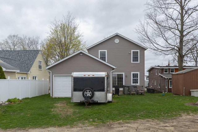 rear view of house featuring driveway, fence, and a yard