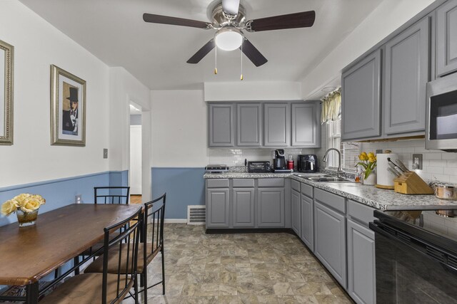8450 Warren Blvd, Center Line, MI 48015 - kitchen featuring a sink, stainless steel microwave, decorative backsplash, a ceiling fan, and gray cabinets