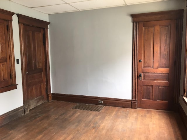empty room featuring baseboards, dark wood-style flooring, and a paneled ceiling