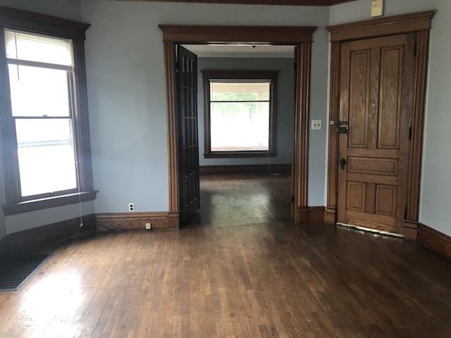 unfurnished room featuring baseboards, hardwood / wood-style flooring, visible vents, and a healthy amount of sunlight