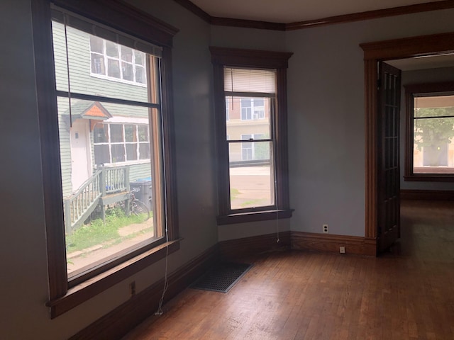 unfurnished room with hardwood / wood-style flooring, a wealth of natural light, visible vents, and baseboards