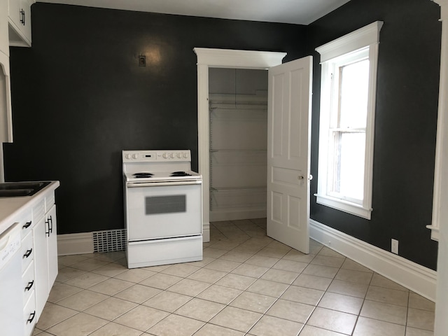 kitchen featuring baseboards, light tile patterned floors, white cabinetry, and white appliances