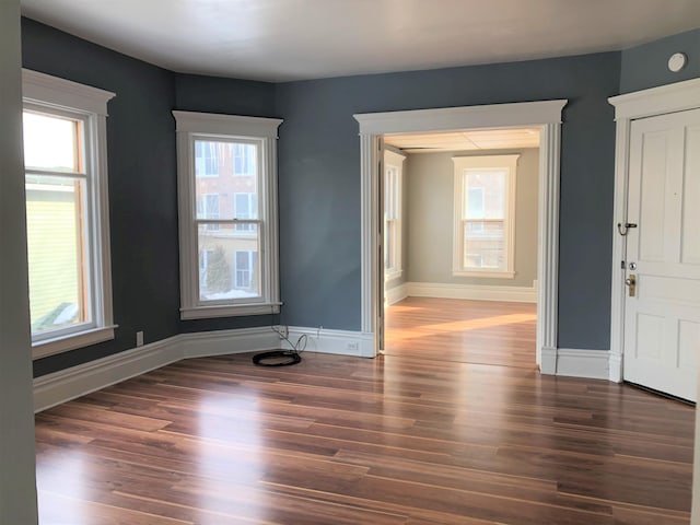 unfurnished room featuring wood finished floors, baseboards, and plenty of natural light
