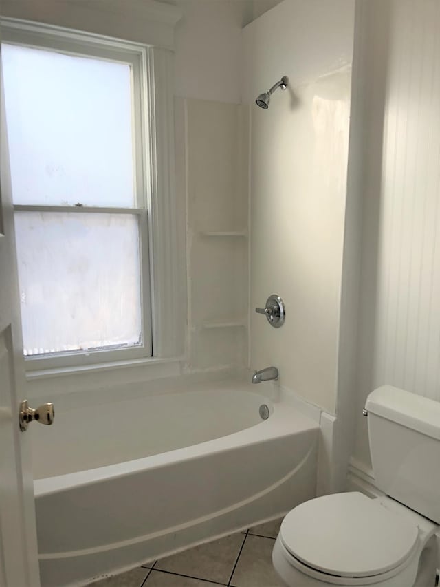 bathroom featuring tile patterned floors, washtub / shower combination, plenty of natural light, and toilet