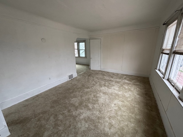 carpeted empty room with arched walkways and visible vents