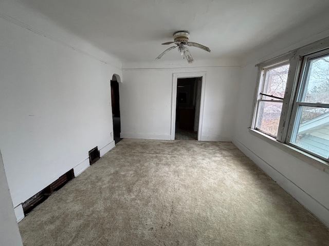 unfurnished bedroom with light carpet, a ceiling fan, arched walkways, and a closet