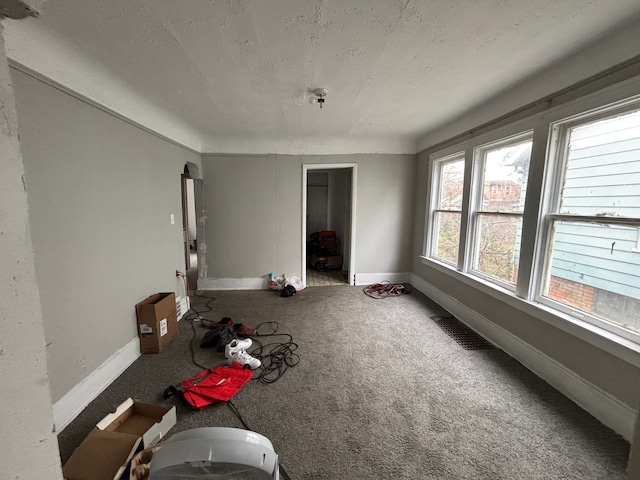 interior space with a textured ceiling, carpet flooring, baseboards, and visible vents