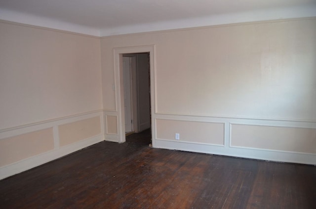 empty room featuring wood finished floors and a decorative wall
