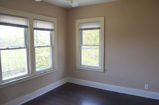 unfurnished room featuring plenty of natural light, baseboards, and dark wood-type flooring