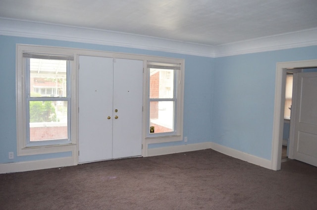 entrance foyer featuring crown molding, baseboards, and dark colored carpet