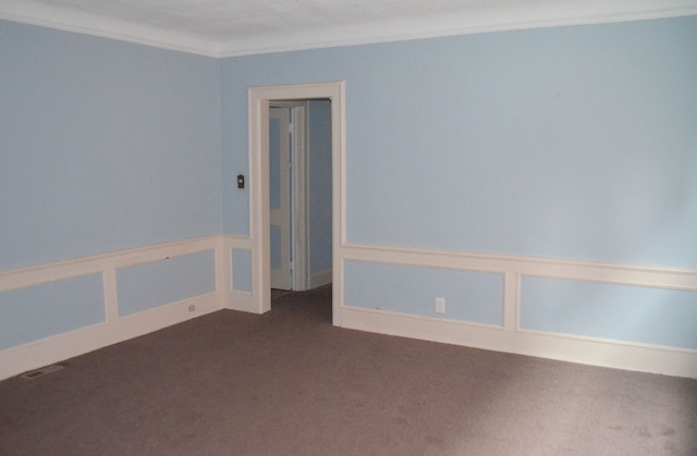 unfurnished room featuring crown molding and dark carpet