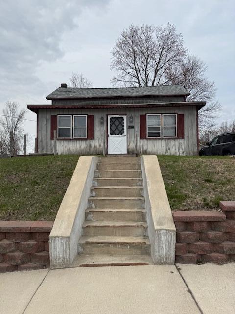 bungalow with a front lawn and stairs