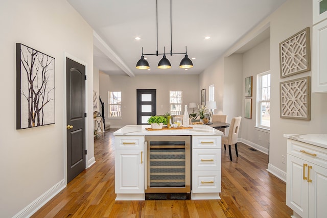 bar featuring beverage cooler, light wood-type flooring, baseboards, pendant lighting, and track lighting