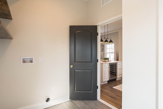 clothes washing area featuring wine cooler, dark wood-type flooring, hookup for a washing machine, baseboards, and hookup for an electric dryer