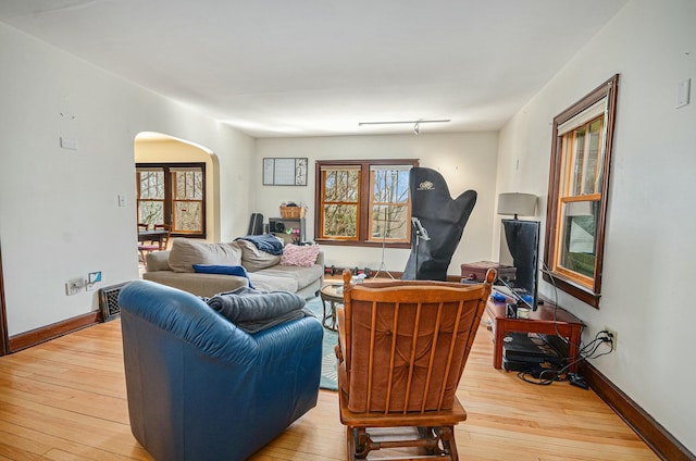 living room with wood-type flooring, arched walkways, and baseboards