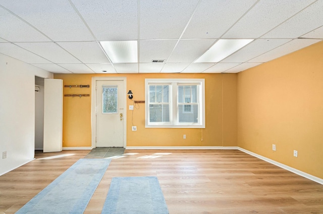 spare room with a drop ceiling, wood finished floors, visible vents, and baseboards