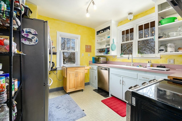 kitchen with a toaster, a sink, open shelves, light countertops, and appliances with stainless steel finishes
