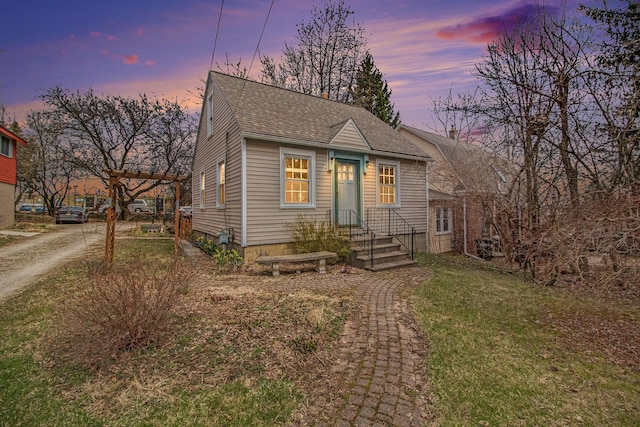 view of front facade with a shingled roof and a front yard
