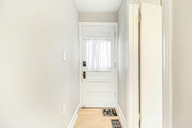 doorway with baseboards, visible vents, and light wood-type flooring