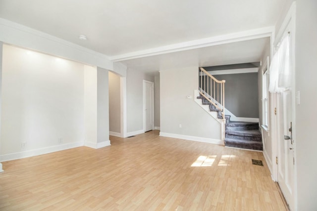 unfurnished living room featuring stairway, baseboards, visible vents, and light wood finished floors