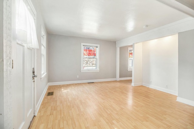 empty room with baseboards, light wood finished floors, and visible vents